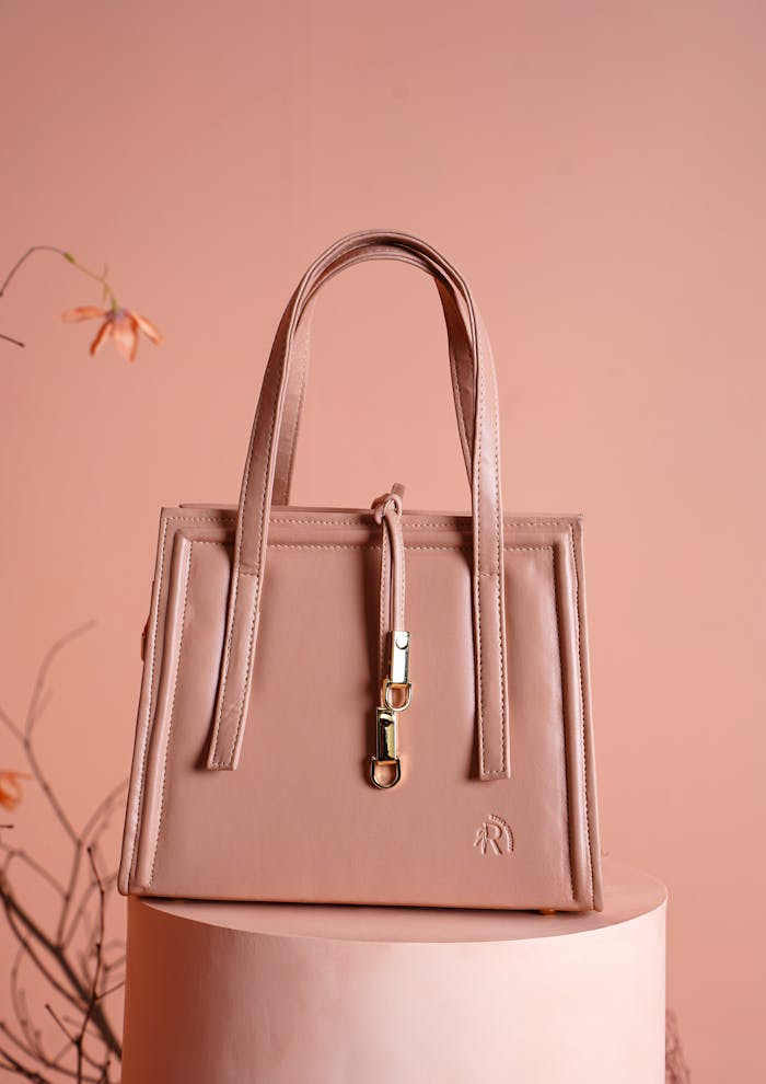 Elegant pink leather handbag displayed in a minimalistic style with a soft floral background.